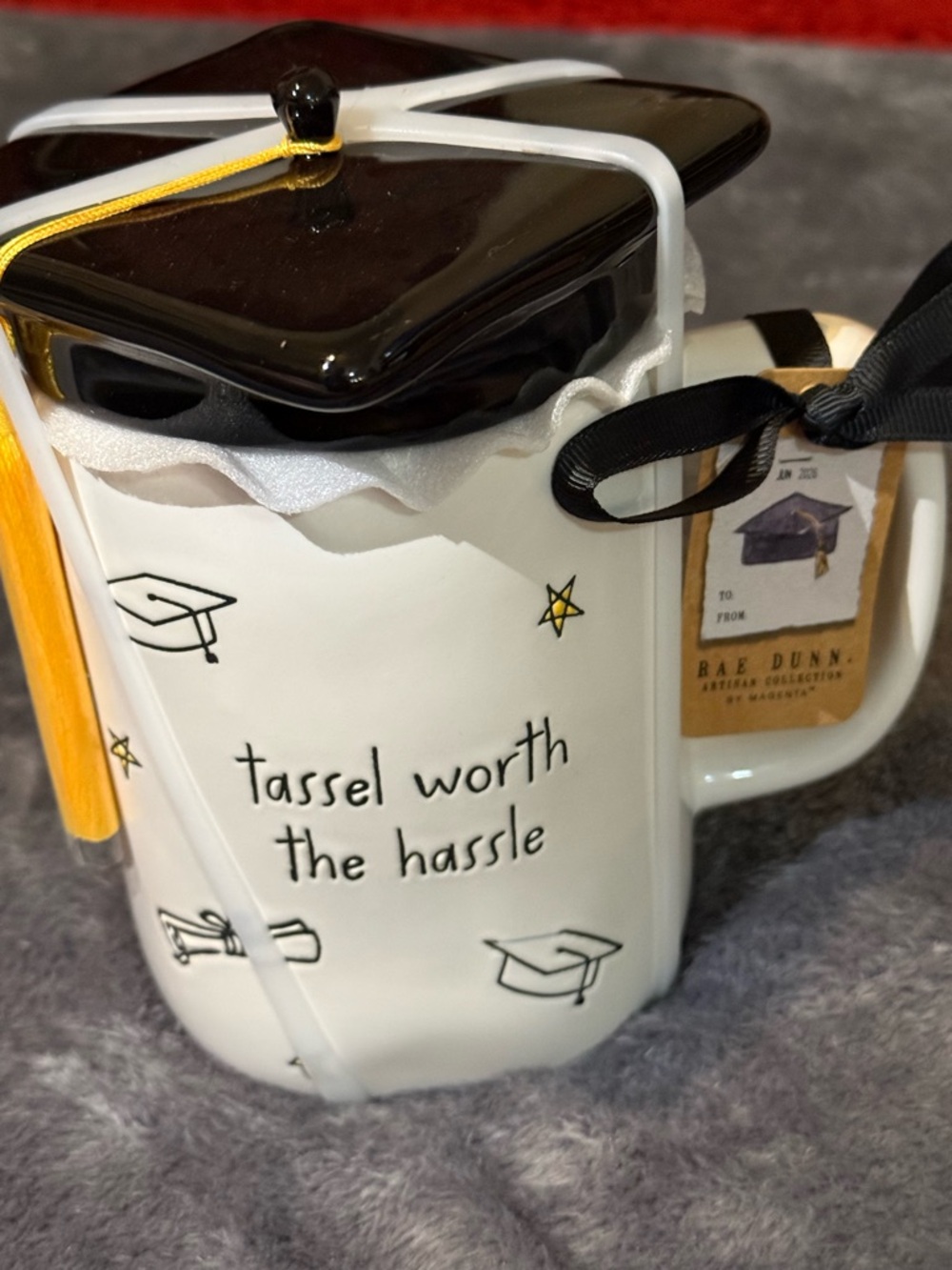 Rae Dunn white ceramic graduation mug with black cap lid and yellow tassel